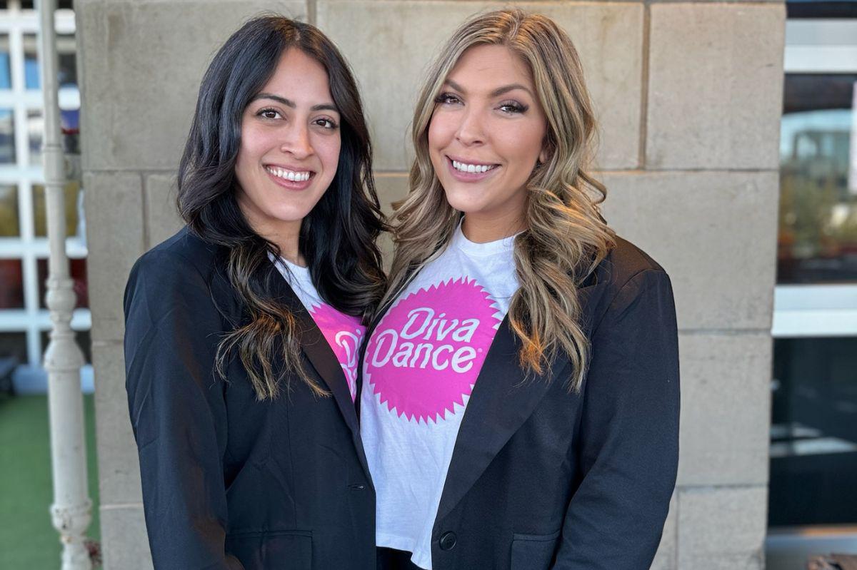 Two DivaDance franchise owners wearing branded tees and blazers smile together.