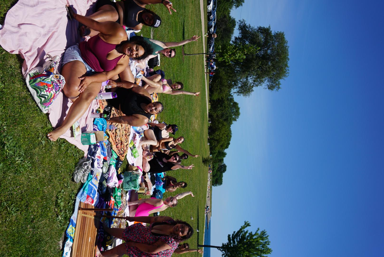 Thirteen DivaDance Chicago community members posing together outdoors on a sunny day at a park